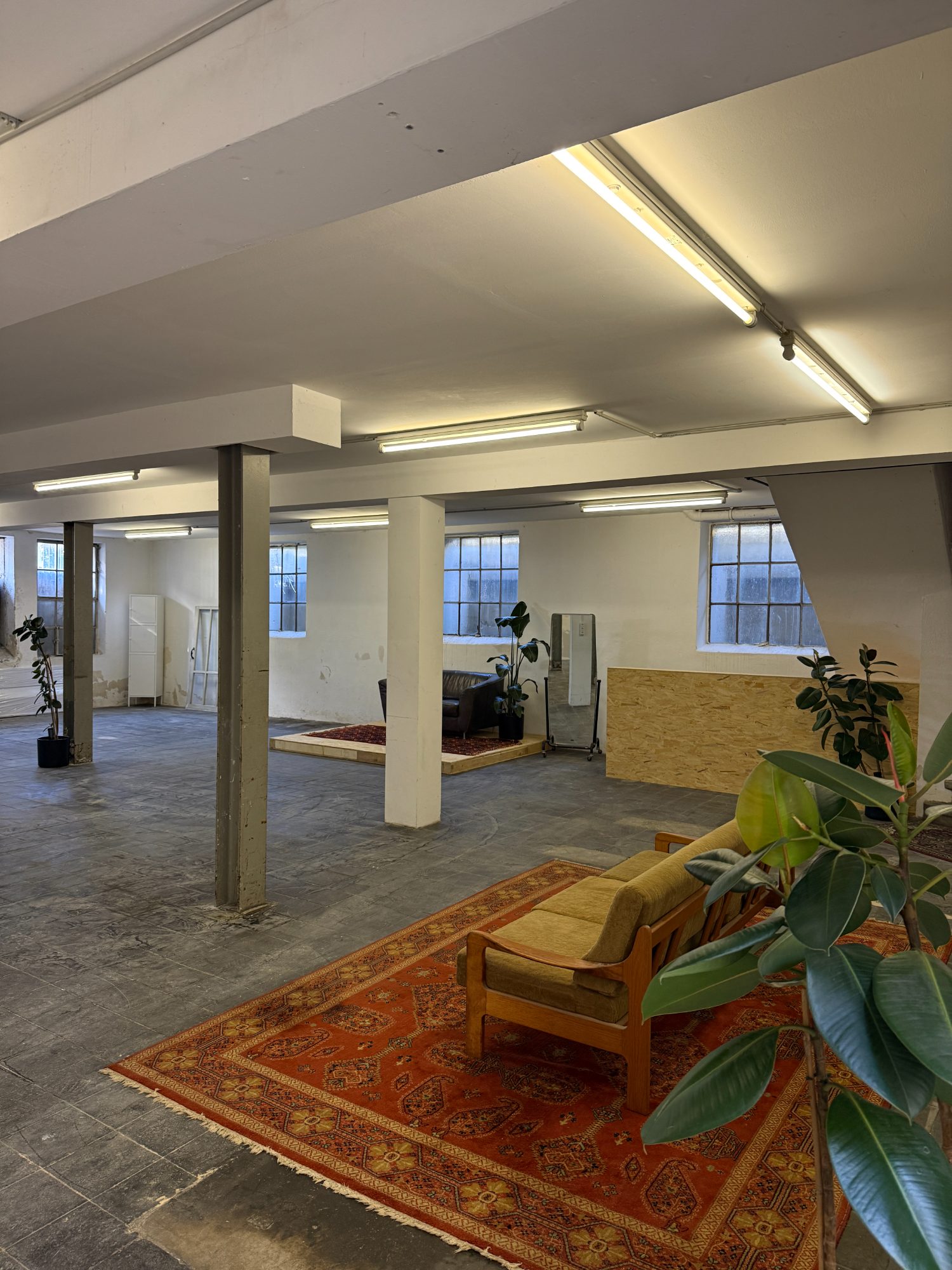 Das Studio: offene Halle mit Säulen, geschliffenem Boden, Lichtschächten, Teppichen und Pflanzen